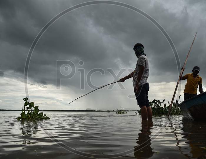 Fishermen catch fish in the swollen Krishna river following the release of surplus water from the Prakasam Barrage in Vijayawada.