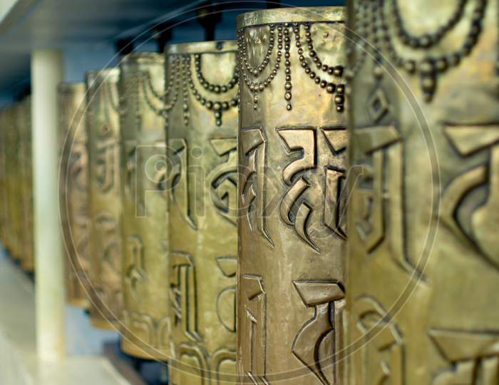 Religious Copper Buddhist Prayer Wheels With A Prayer Mantra Written On It In A Pilgamage Spot In A Monastary