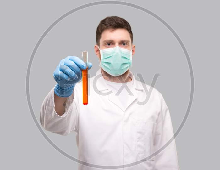 Male Doctor Showing Blood Analysis Wearing Medical Mask And Gloves. Laboratory Virus Concept. Red Liquid