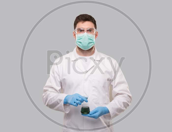 Male Doctor Wearing Medical Mask And Gloves Showing Flask With Colorfull Liquid. Science, Medical, Virus Concept