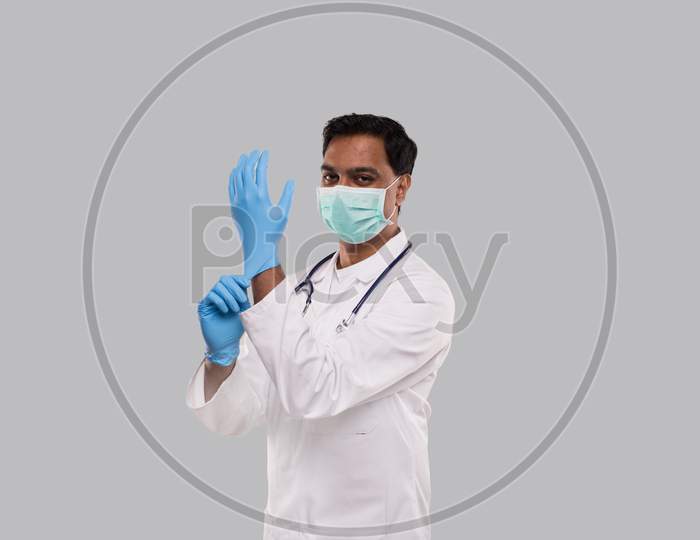 Doctor Puts On Gloves And Wearing Medical Mask Isolated. Indian Man Doctor Protection Mask Workwear. Medical Concept Corona Virus.