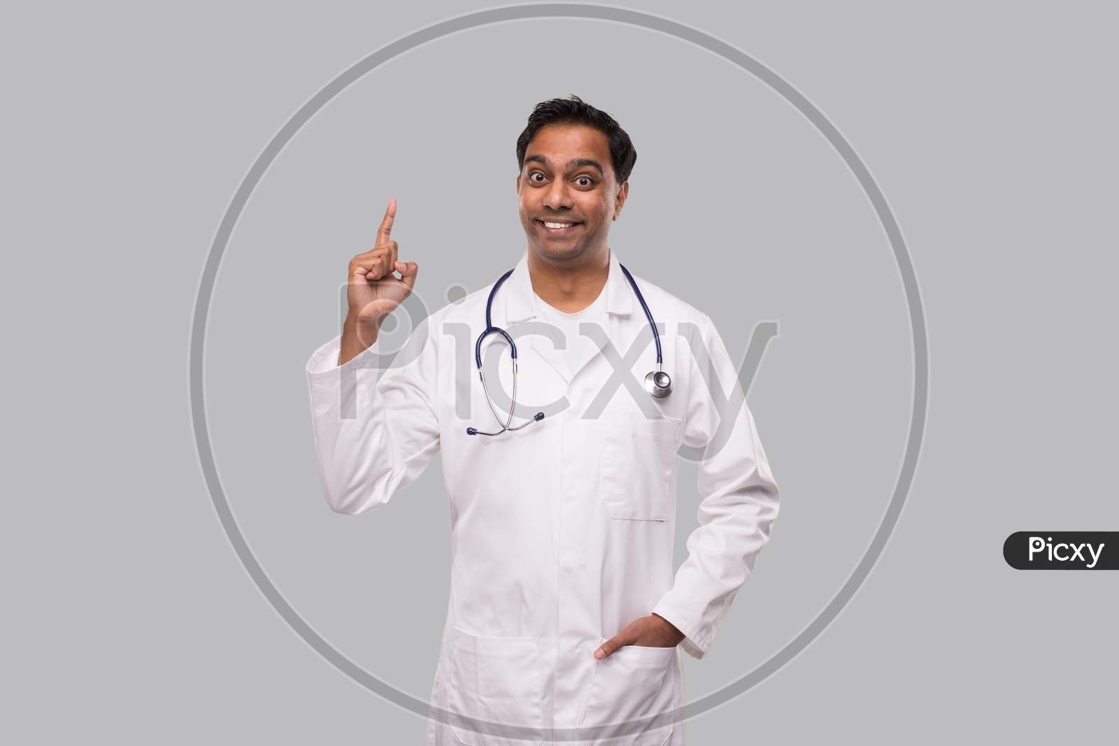 Indian Man Doctor Pointing Up And Watching In Camera. Isolated