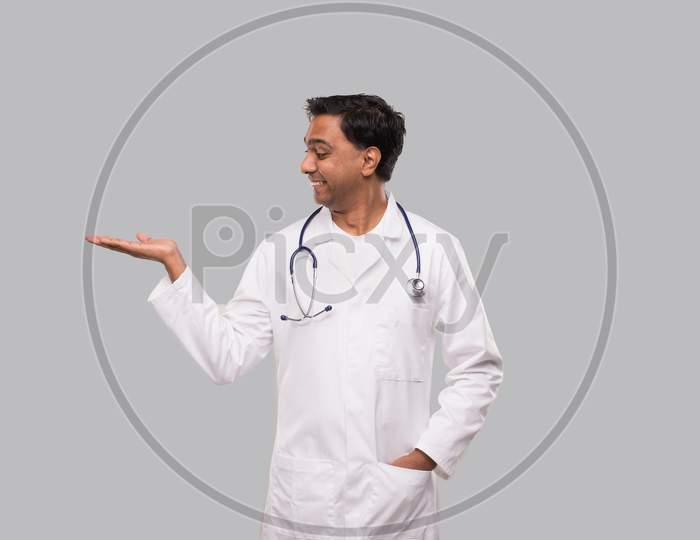 Doctor Holding Hand To Side Watching To Side Isolated. Indian Man Doctor Sign
