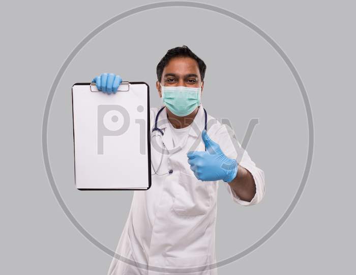 Doctor Holding Clipboard Showing Thumb Up Wearing Medical Mask And Gloves Isolated. Indian Man Doctor Blank Clipboard In Hands