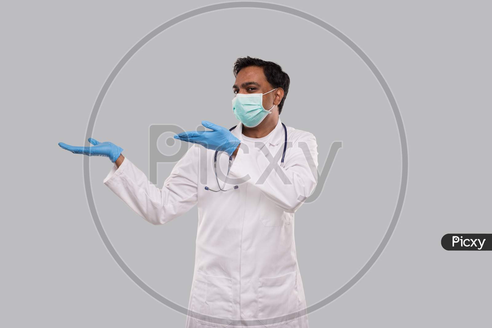 Doctor Holding Open Hands To Side Wearing Medical Mask And Gloves Watching To Side Isolated. Indian Man Doctor Excited Sign