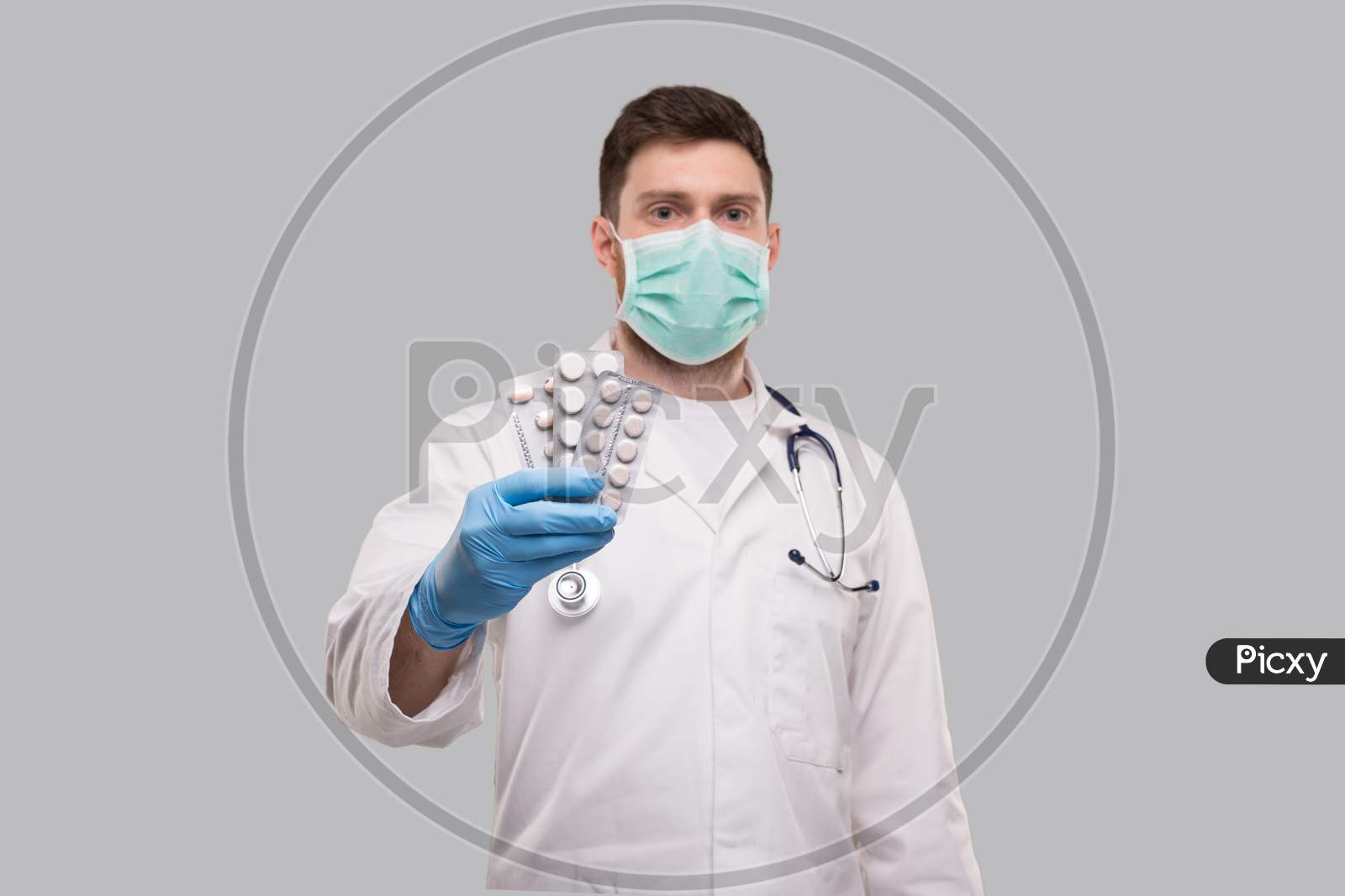 Man Doctor Showing Pills Wearing Medical Mask. Doctor Holding Tablets. Corona Virus Concept.