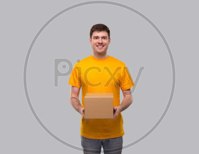 Delivery Man With Box In Hands. Yellow Tshirt Delivery Boy. Home Delivery. Quarantine Hero. Man Smiling