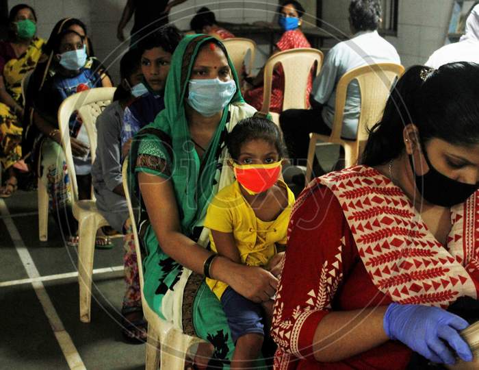 Residents of a locality wait be screened at a camp, at a marriage hall, which has temporarily been converted into a coronavirus testing centre, in  Mumbai, India on July 17, 2020.