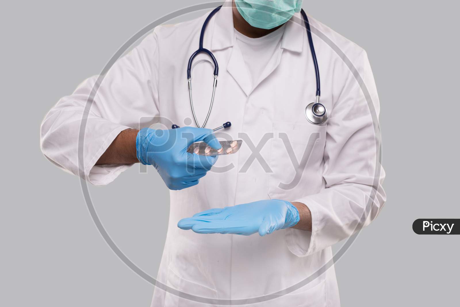 Man Doctor Taking Pills Wearing Medical Mask And Gloves. Doctor Holding Tablets. Indian Man Doctor Isolated. Close Up