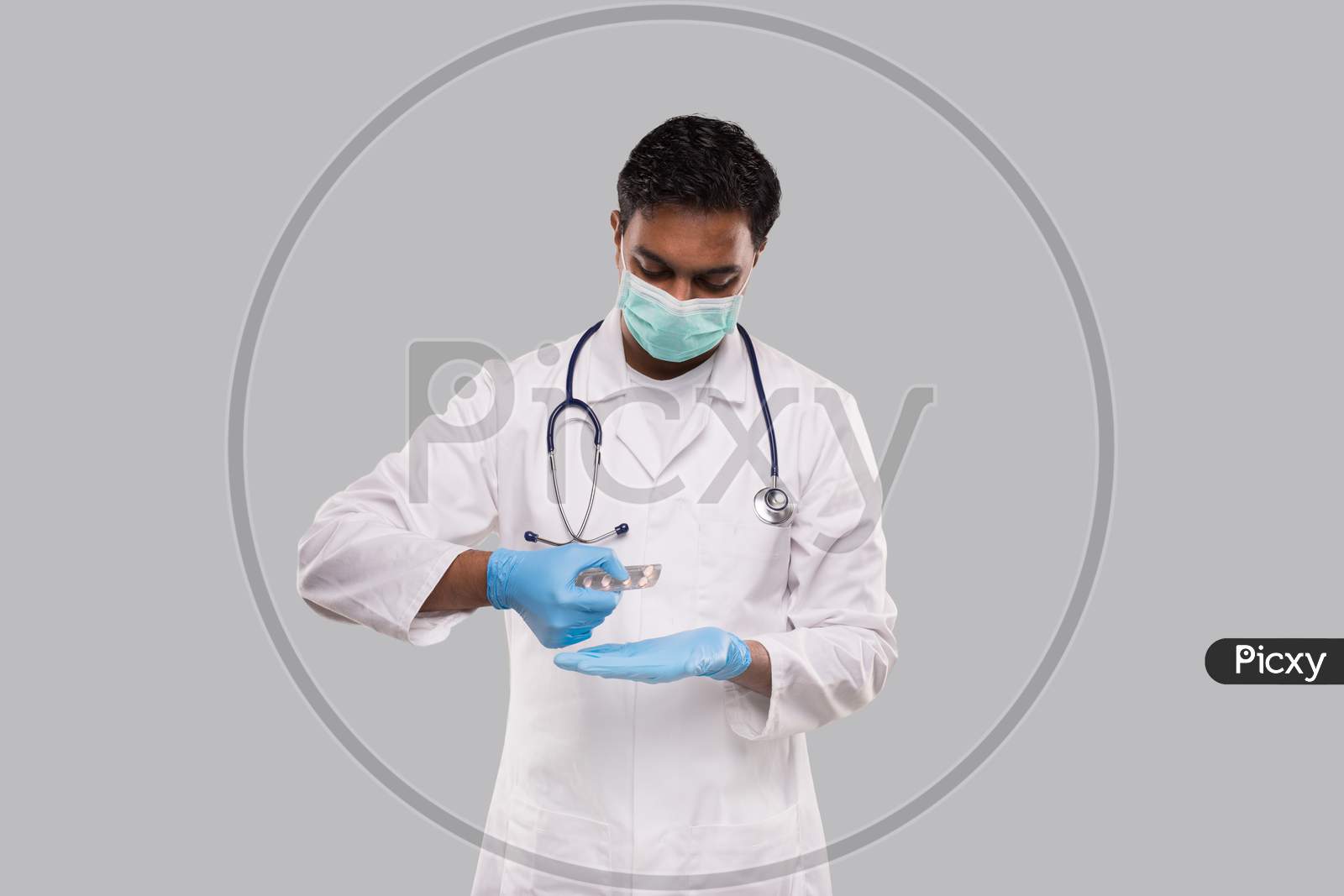 Man Doctor Taking Pills Wearing Medical Mask And Gloves. Doctor Holding Tablets. Indian Man Doctor Isolated.