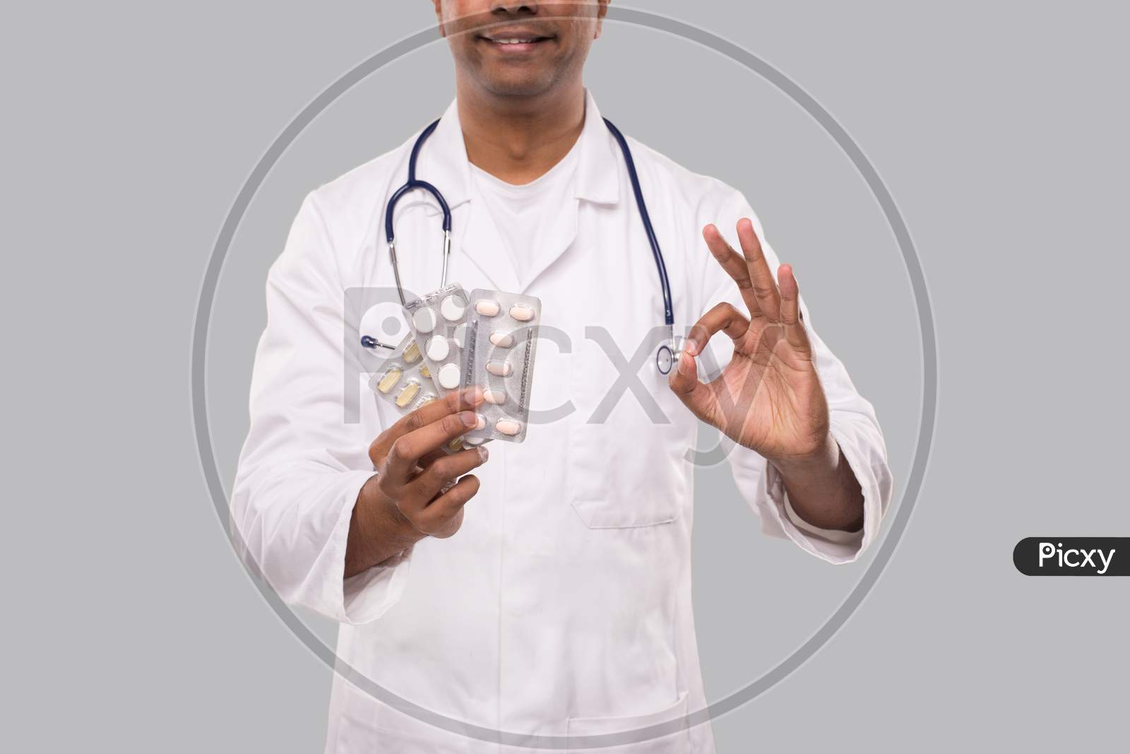 Man Doctor Showing Pills And Ok Sign Close Up. Doctor Holding Tablets. Indian Man Doctor Isolated.