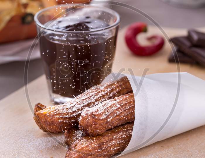 fresh fried pumpkin churros with chocolate on cutting board. Vertical image.