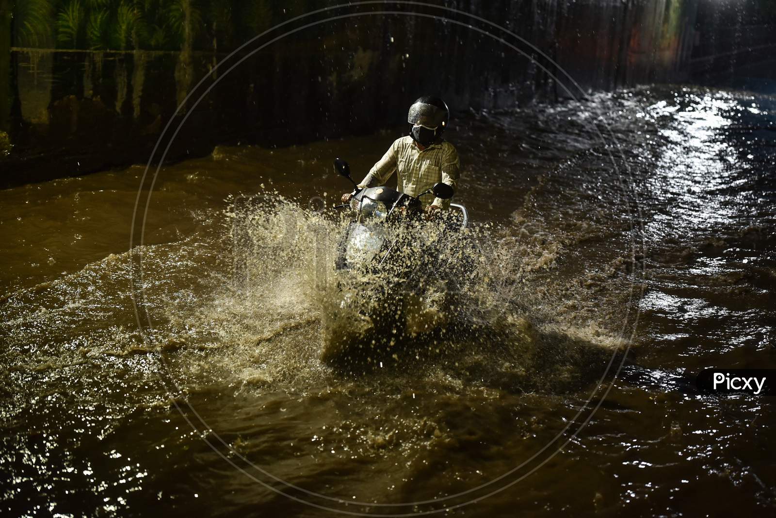 A commuter drives through a water-logged road following heavy rain in Vijayawada.