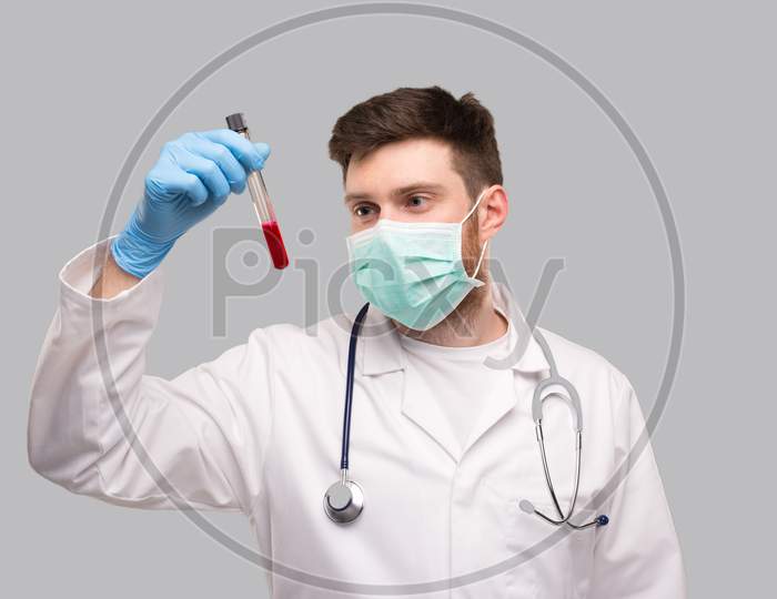 Male Doctor Checking Intently Blood Analysis Wearing Medical Mask And Gloves. Portrait. Virus Analysis Concept