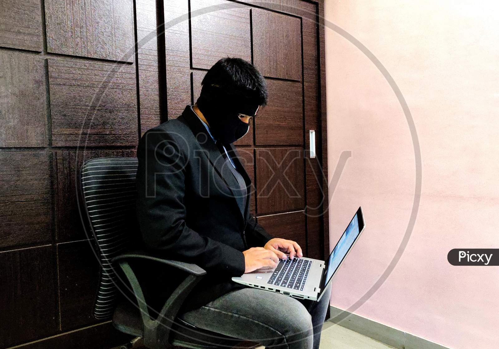 A young man wearing mask and is working on a laptop