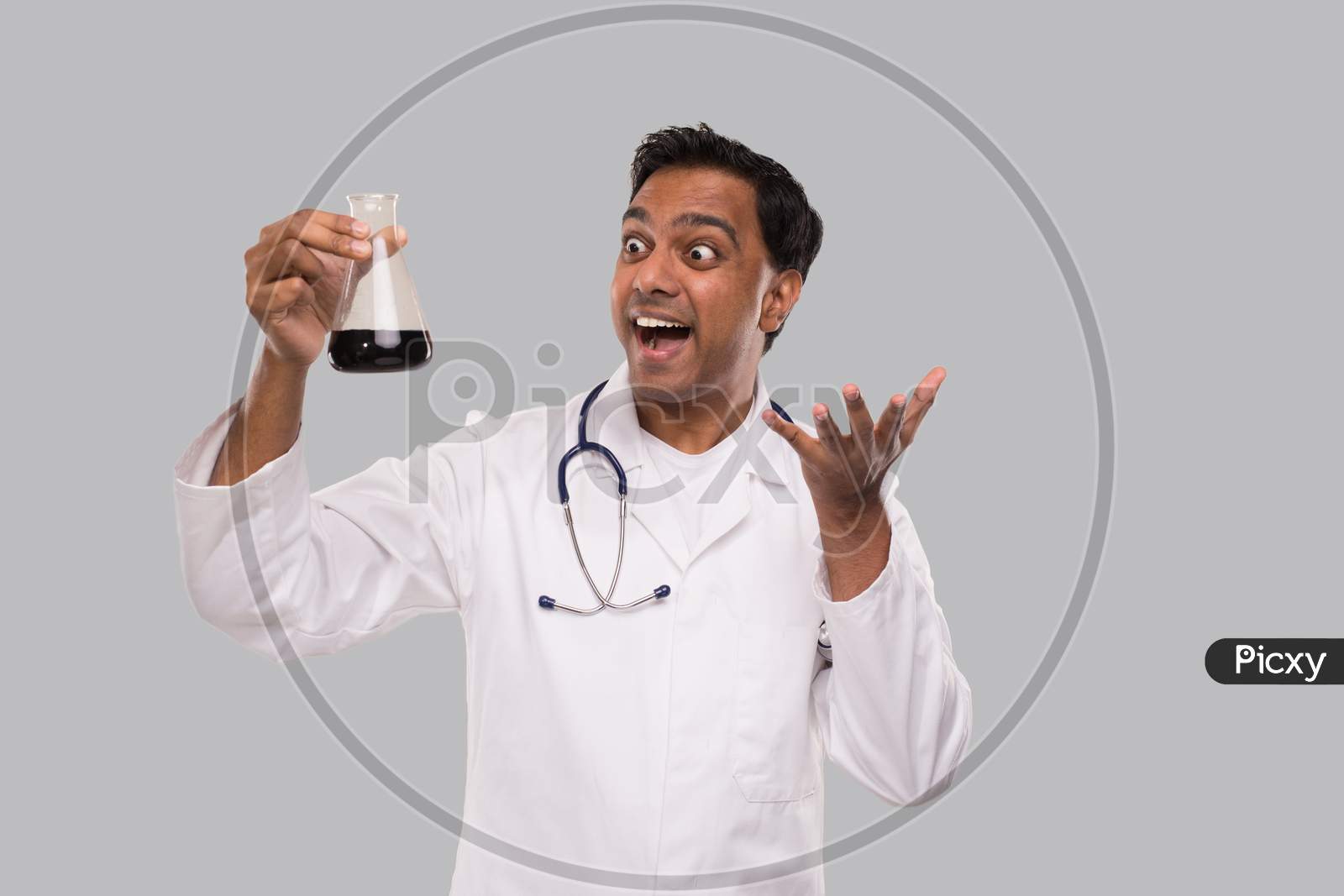 Male Doctor Excited Watching Flask With Colorfull Liquid Isolated. Science, Medical, Virus Concept. Indian Man Doctor Smilling.