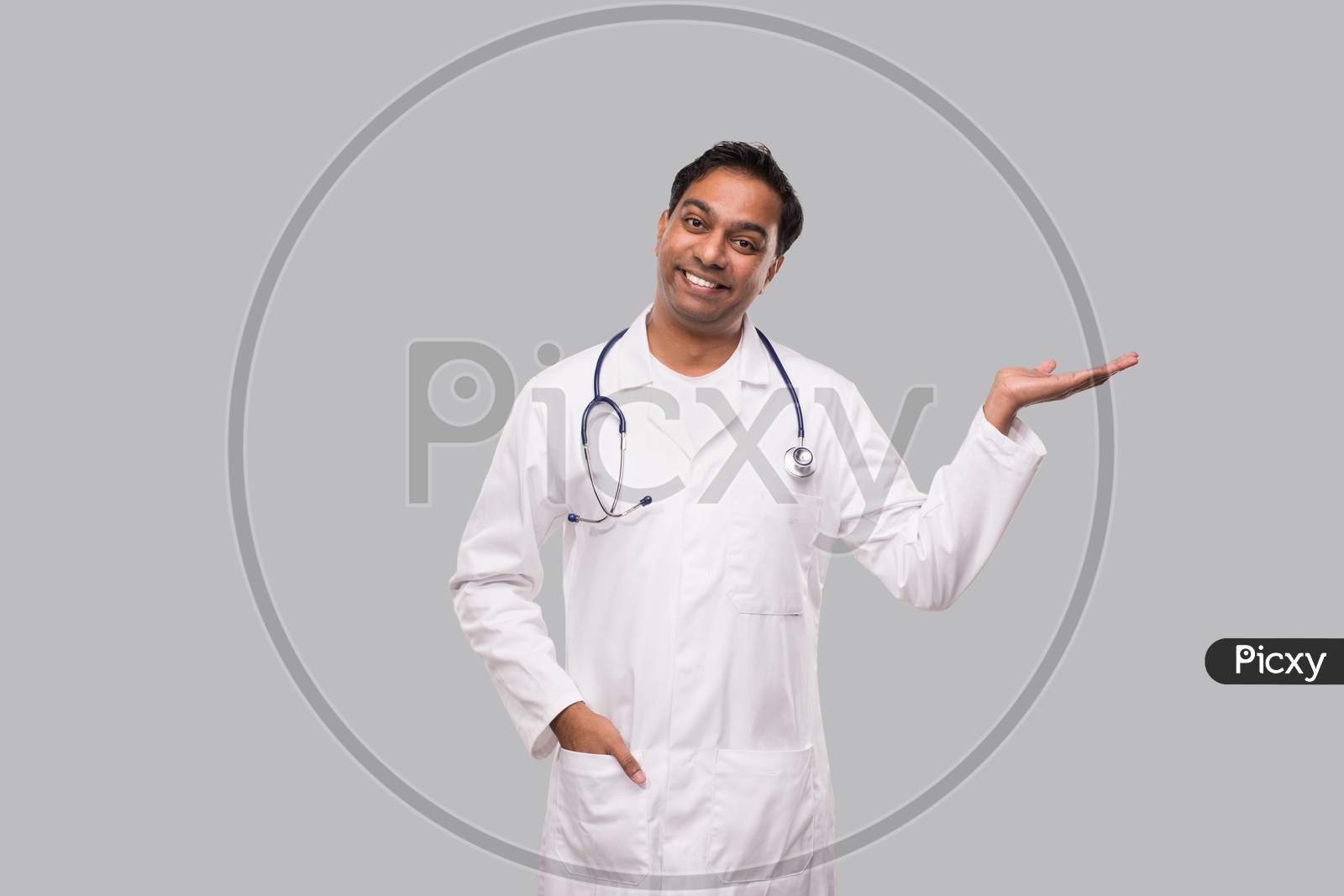 Doctor Holding Hand To Side Watching To Camera Isolated. Indian Man Doctor Sign