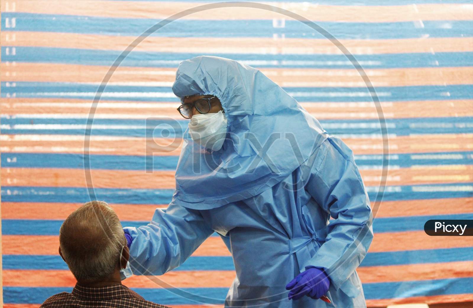 A healthcare worker wearing personal protective equipment (PPE) collects a swab sample from a resident during a check-up campaign, at a marriage hall, which is temporarily converted into a coronavirus testing centre, in Mumbai, India on July 17, 2020.