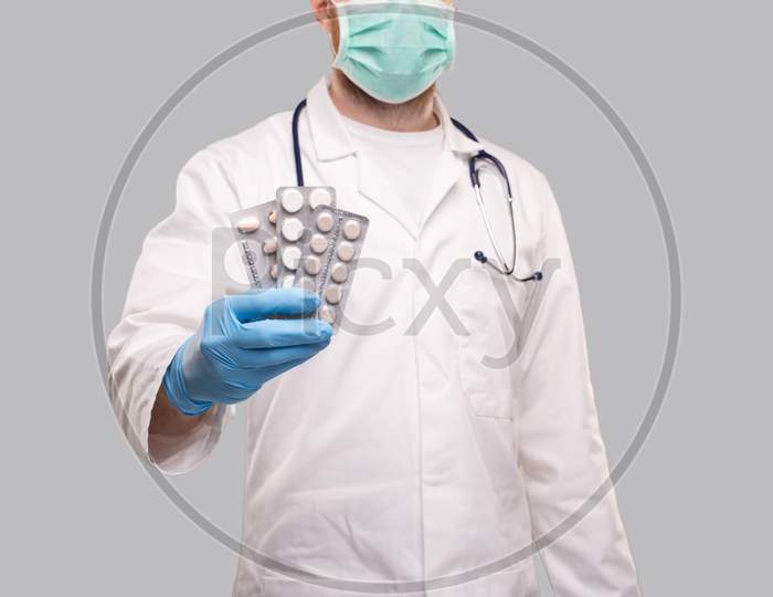 Man Doctor Showing Pills Wearing Medical Mask. Doctor Holding Tablets. Corona Virus Concept. Pills Close Up. Focus On Tablets