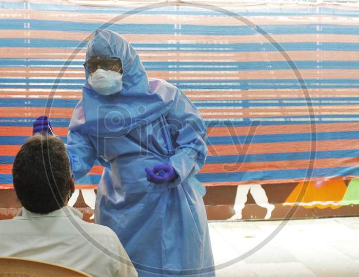 A Healthcare Worker Wearing Personal Protective Equipment(PPE) Collects A Swab Sample From A Resident During A Check Up Campaign At A Marriage Hall Which Is Temporarily Converted Into A Coronavirus Testing Centre In Mumbai India On July 17 2020.