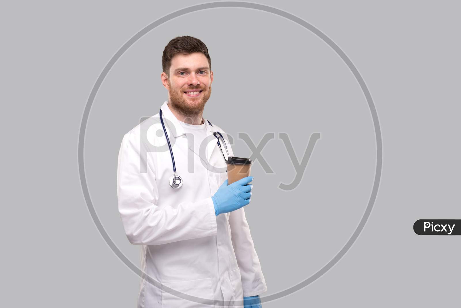 Doctor Holding Coffe Take Away Cup Wearing Gloves And Smiling Isolated