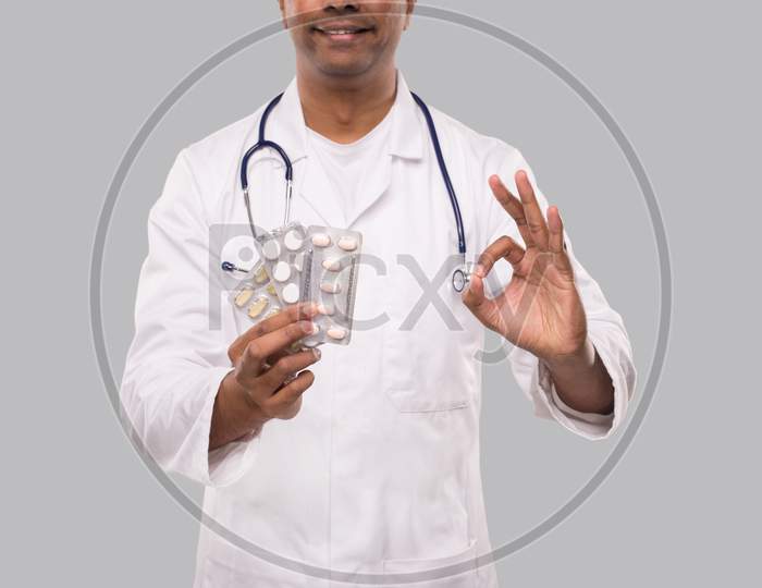 Man Doctor Showing Pills And Ok Sign Close Up. Doctor Holding Tablets. Indian Man Doctor Isolated.
