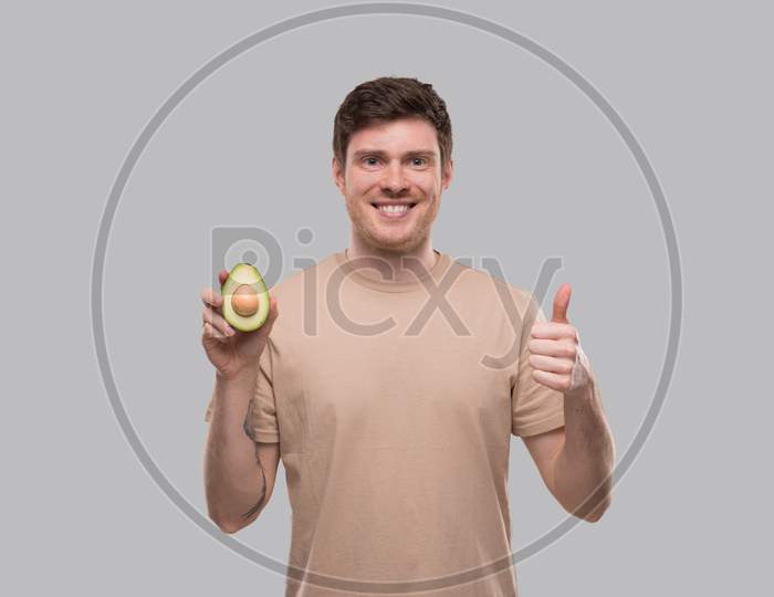 Man Showing Avocado And Thumb Up Isolated. Avocado Cut In Half