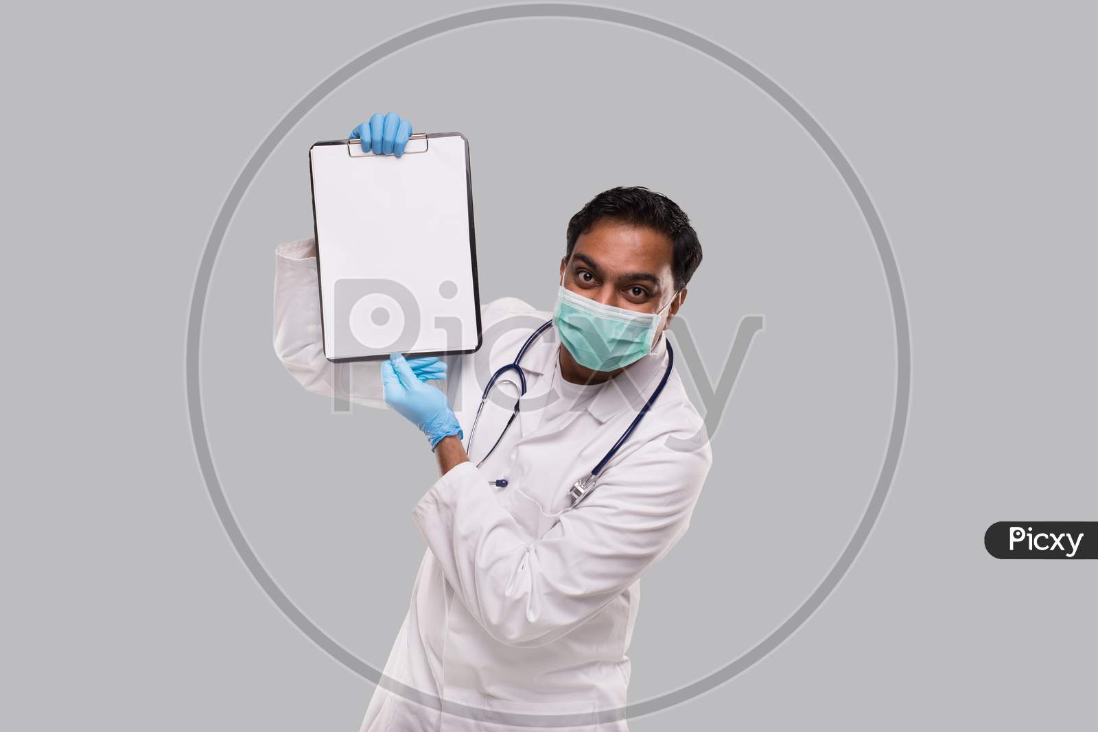 Doctor Showing Clipboard Wearing Medical Mask And Gloves Isolated. Indian Man Doctor Blank Clipboard In Hands