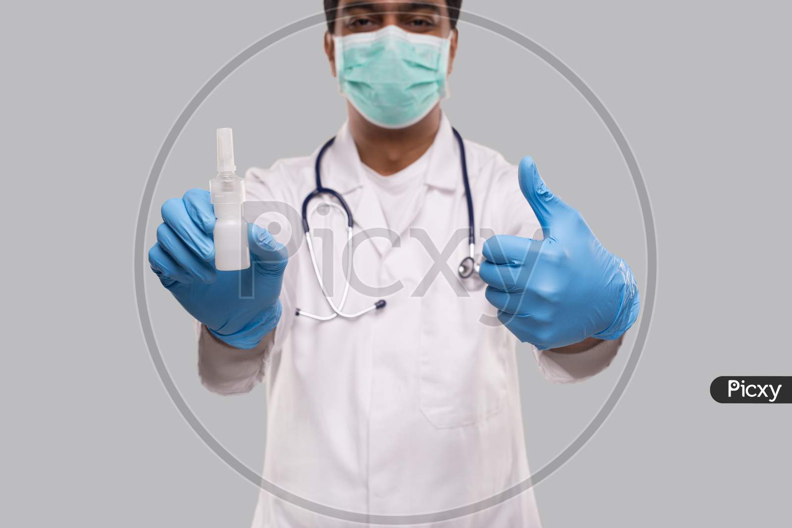 Doctor Showing Nose Spray And Thumb Up Wearing Medical Mask And Gloves Close Up. Indian Man Doctor Nasal Spray. Corona Virus Concept. Isolated