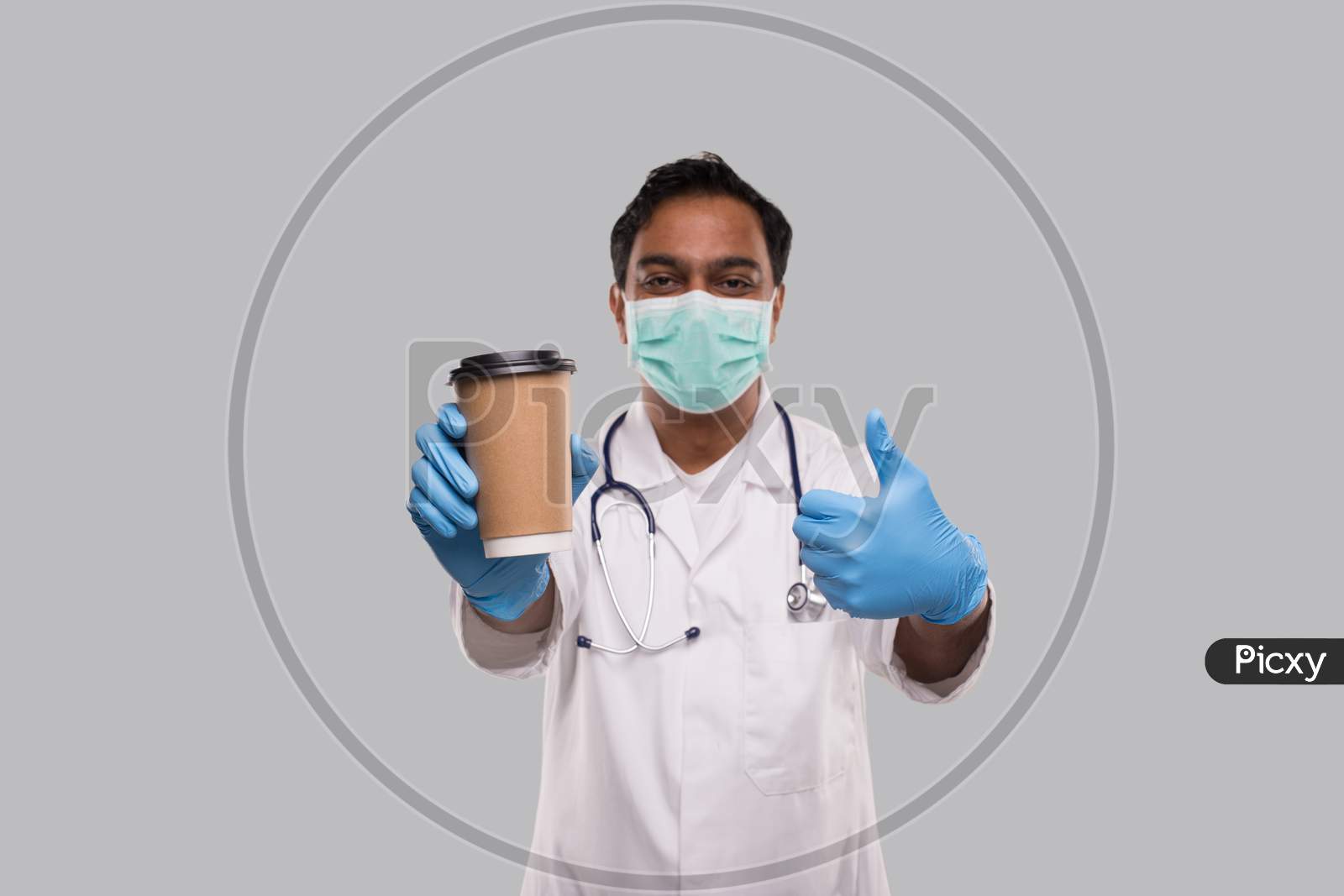Indian Man Doctor Holding Coffee Take Away Cup Wearing Medical Mask And Gloves Showing Thumb Up Isolated. Indian Doctor Holding Coffee To Go Cup.