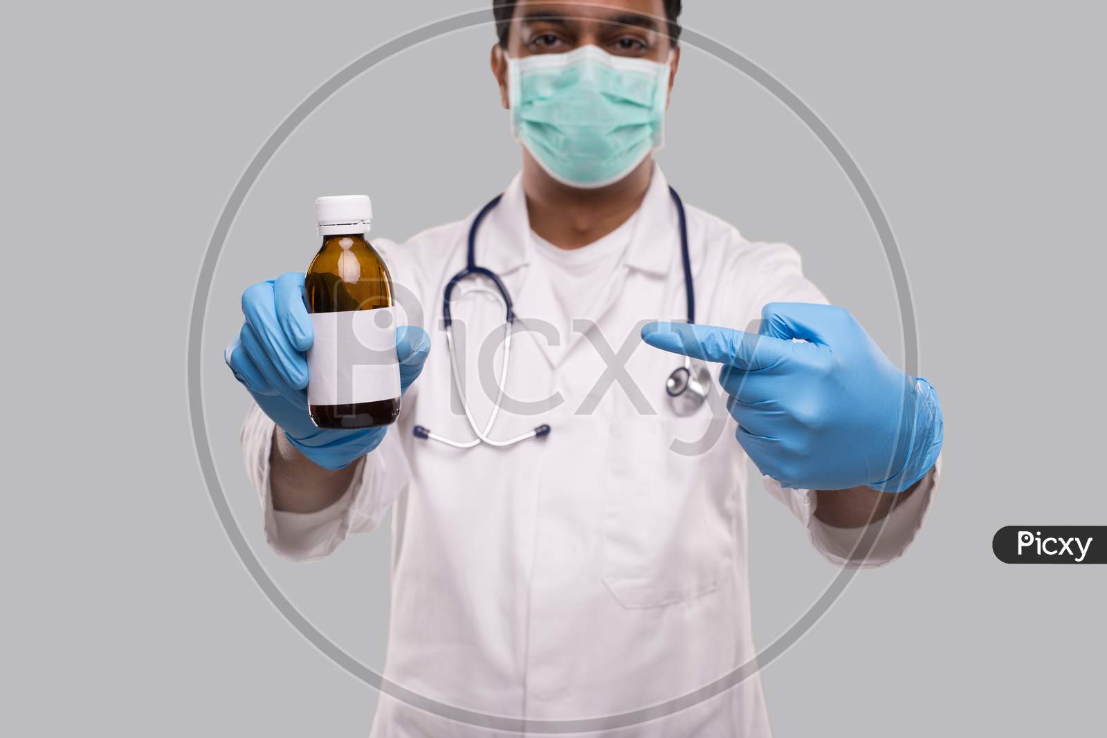 Indian Man Doctor Pointing At Cough Syrup Wearing Medical Mask And Gloves. Hands Wash Antiseptic. Corona Virus Concept. Isolated