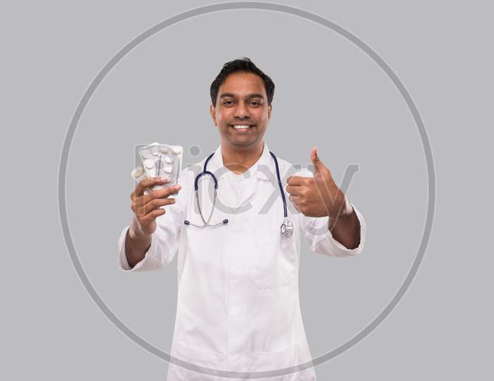 Man Doctor Showing Pills And Thumb Up. Doctor Holding Tablets. Indian Man Doctor Isolated.