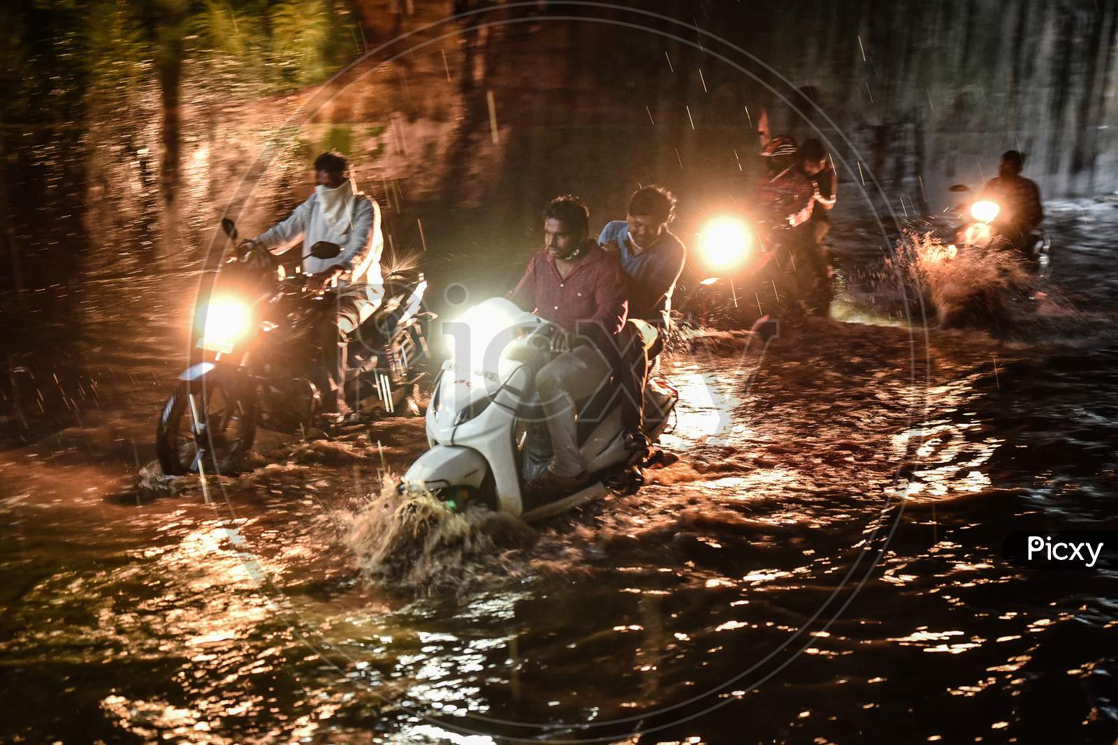 Commuters drive through a water-logged road following heavy rain in Vijayawada.