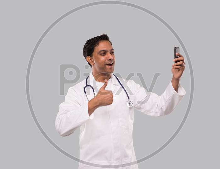 Doctor Having Video Call On Phone Showing Thumb Up Isolated. Indian Man Doctor Video Call. Medicine Online. Doctor Using Phone.