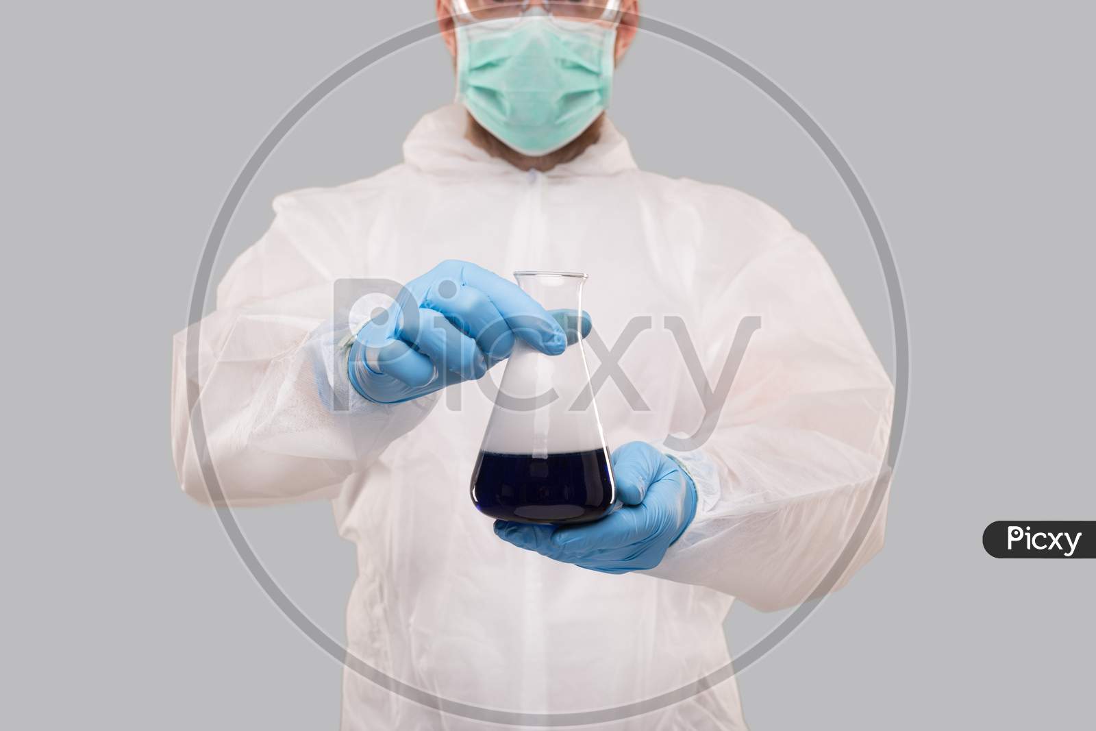 Male Laboratory Worker In Chemical Suit, Wearing Medical Mask And Glasses Showing Flask With Colorfull Liquid. Science, Medical, Virus Concept
