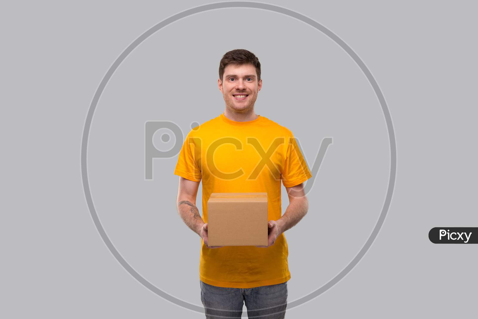 Delivery Man With Box In Hands. Yellow Tshirt Delivery Boy. Home Delivery. Quarantine Hero. Man Smiling