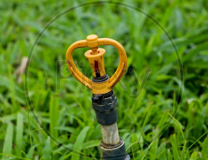 Yellow Color Water Sprinkler On Plastic Pipe Placed In The Garden