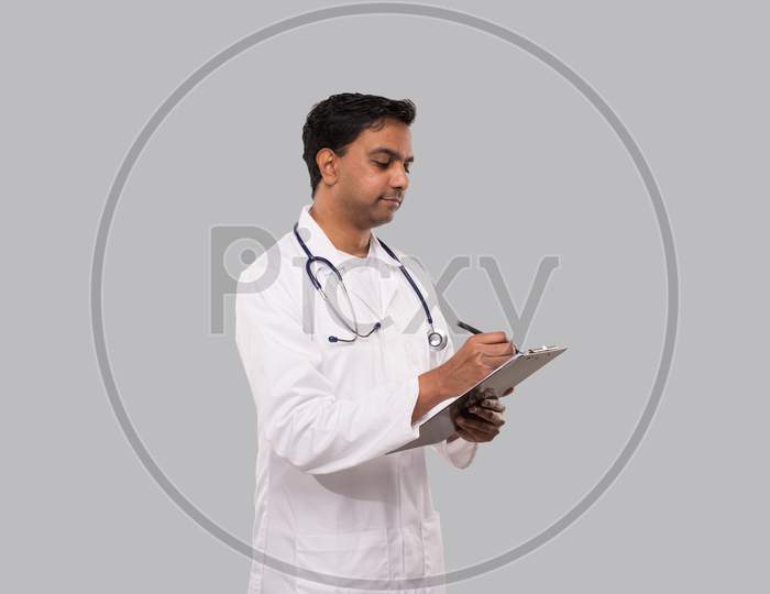 Doctor Writing In Clipboard Watching At Clipboard. Indian Man Doctor Clipboard Isolated