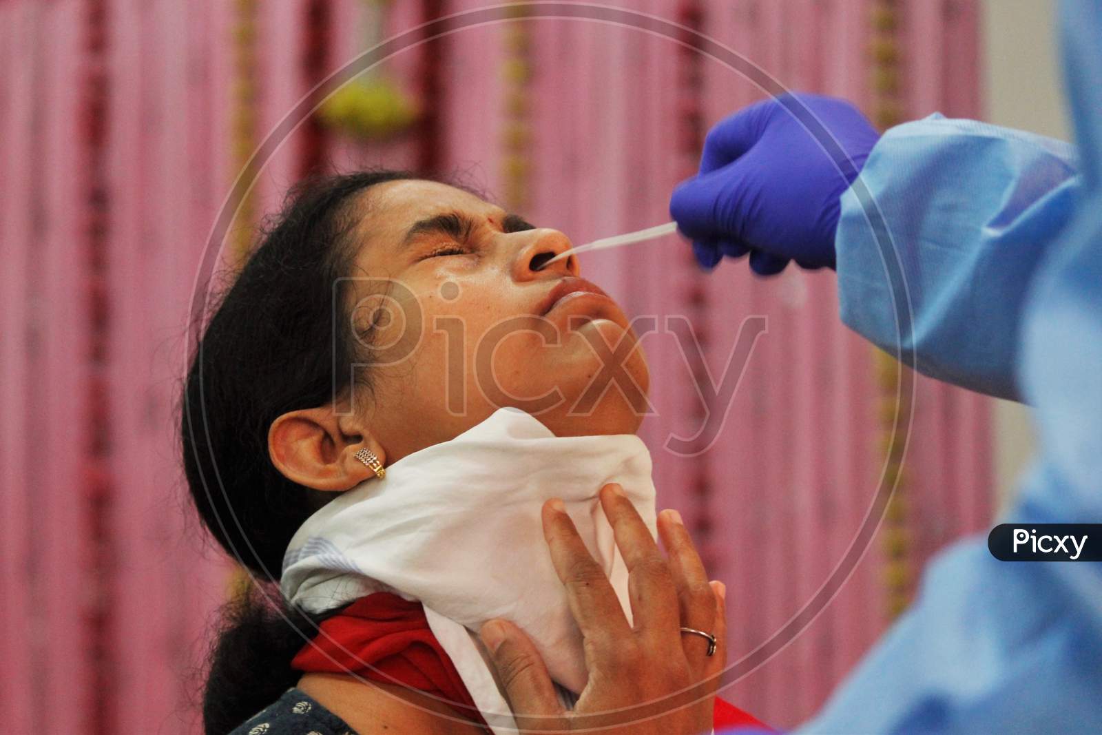 A healthcare worker wearing personal protective equipment (PPE) collects a swab sample from a resident during a check-up campaign, at a marriage hall, which is temporarily converted into a coronavirus testing centre, in Mumbai, India on July 17, 2020.