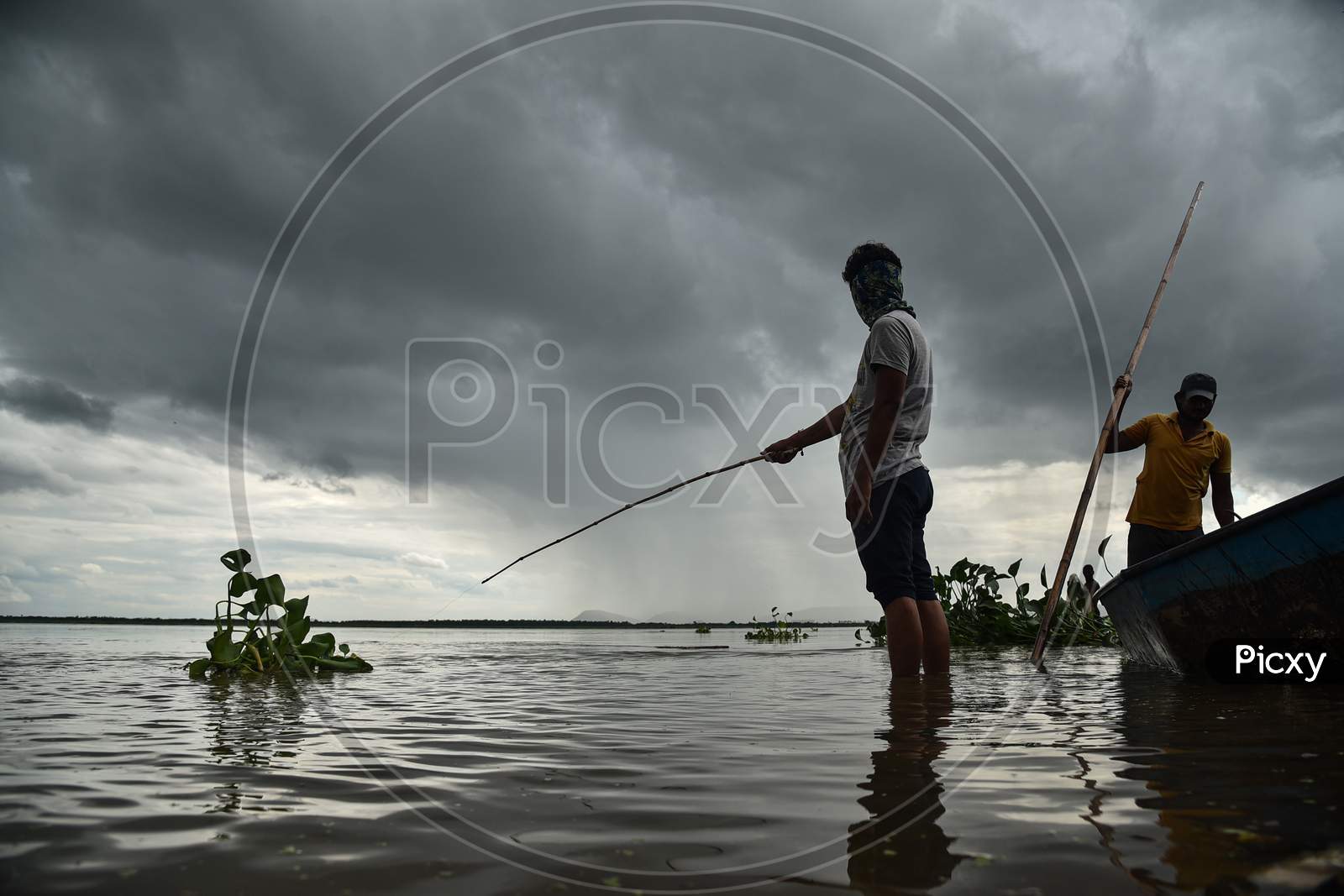 Fishermen catch fish in the swollen Krishna river following the release of surplus water from the Prakasam Barrage in Vijayawada.