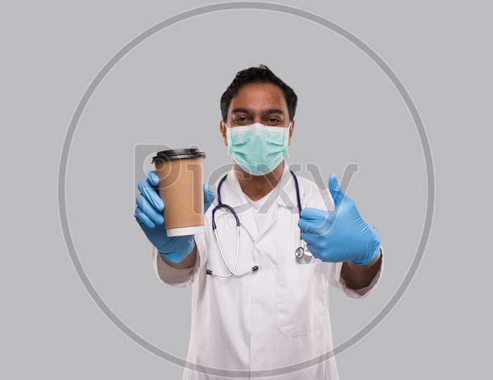 Indian Man Doctor Holding Coffee Take Away Cup Wearing Medical Mask And Gloves Showing Thumb Up Isolated. Indian Doctor Holding Coffee To Go Cup.