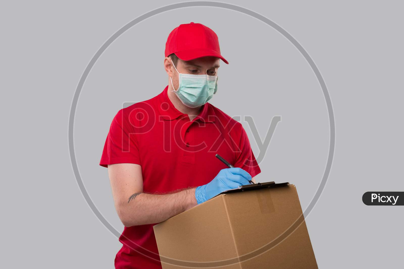 Delivery Man Wearing Medical Mask And Gloves Writing In Clipboard With Box In Hands. Delivery Boy Home Delivery.