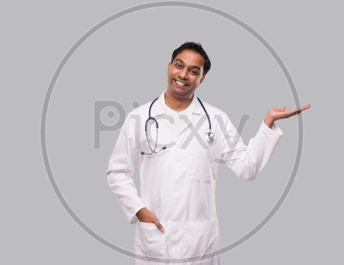 Doctor Holding Hand To Side Watching To Camera Isolated. Indian Man Doctor Sign