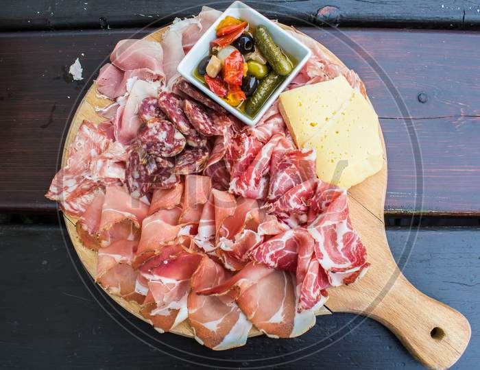 spanish tapas - slices of cured pork ham jamon with melon and red wine on wooden background