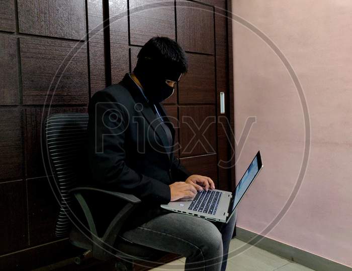 A Young Man Wearing Mask And Is Working On A Laptop