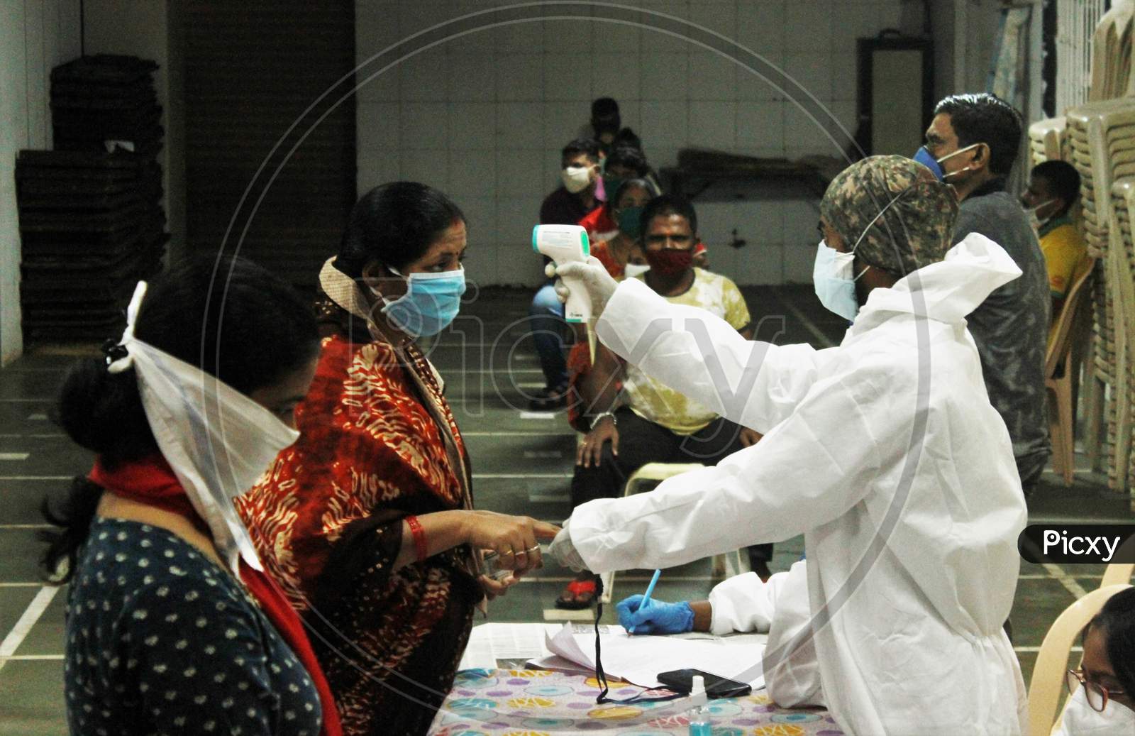 A Healthcare Worker Wearing Personal Protective Equipment(PPE) Checks The Temperature Of A Resident During A Check Up Campaign At A Marriage Hall Which Is Temporarily Converted Into A Coronavirus Testing Centre In Mumbai India On July 17 2020