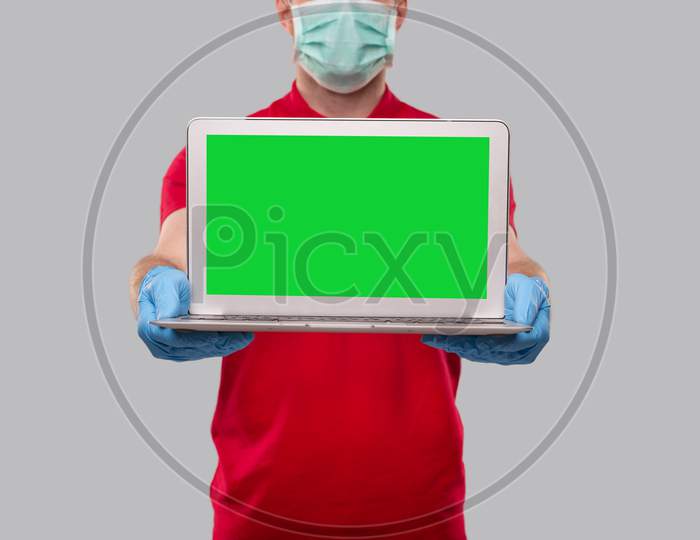 Delivery Man Wearing Medical Mask And Gloves Showing Laptop Green Screen Close Up. Home Orders, Quarantine Delivery, Shopping Online, Freelance Worker Concept.