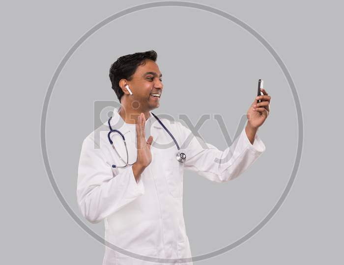 Doctor Having Video Call On Phone Wireless Earphones Isolated. Indian Man Doctor Video Call. Medicine Online. Doctor Using Phone.