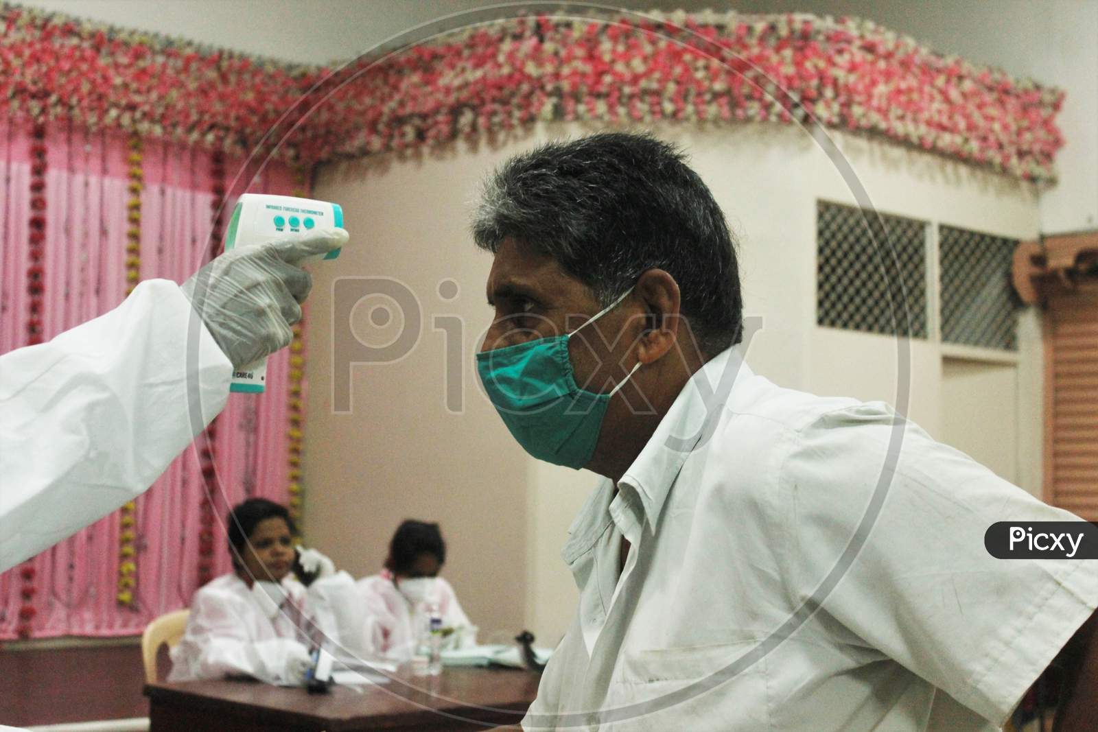 A Healthcare Worker Wearing Personal Protective Equipment(PPE) Checks The Temperature Of A Resident During A Check Up Campaign At A Marriage Hall Which Is Temporarily Converted Into A Coronavirus Testing Centre In Mumbai India On July 17 2020