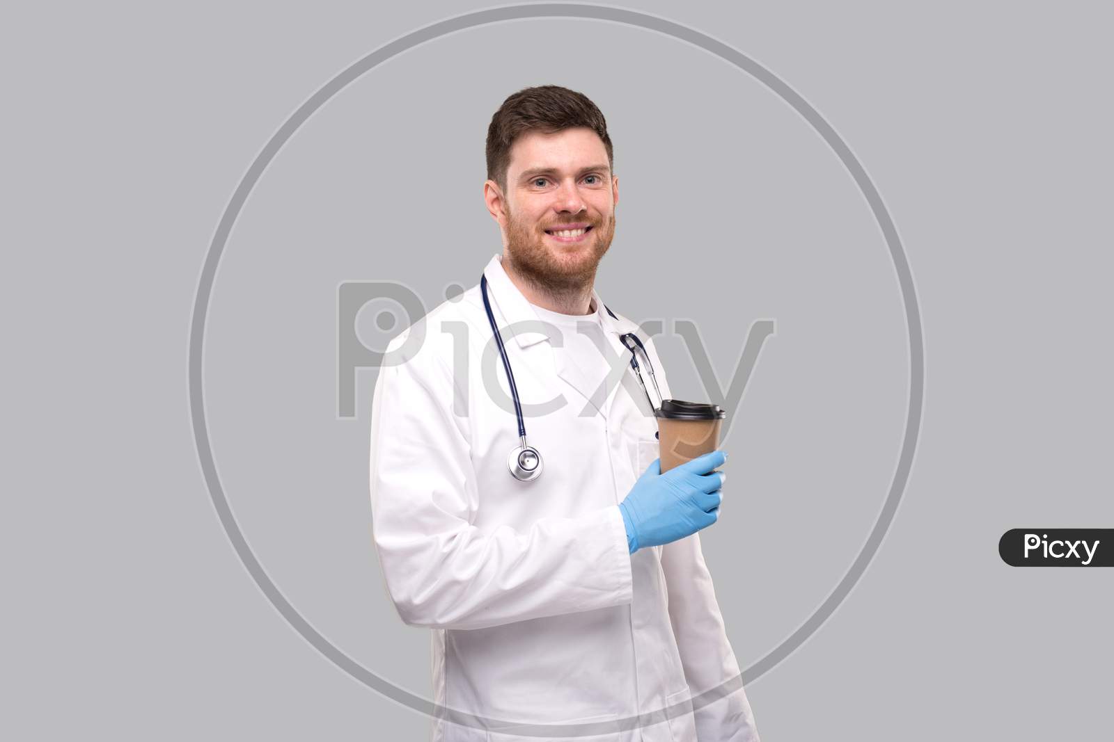 Doctor Holding Coffe Take Away Cup Wearing Gloves And Smiling Isolated